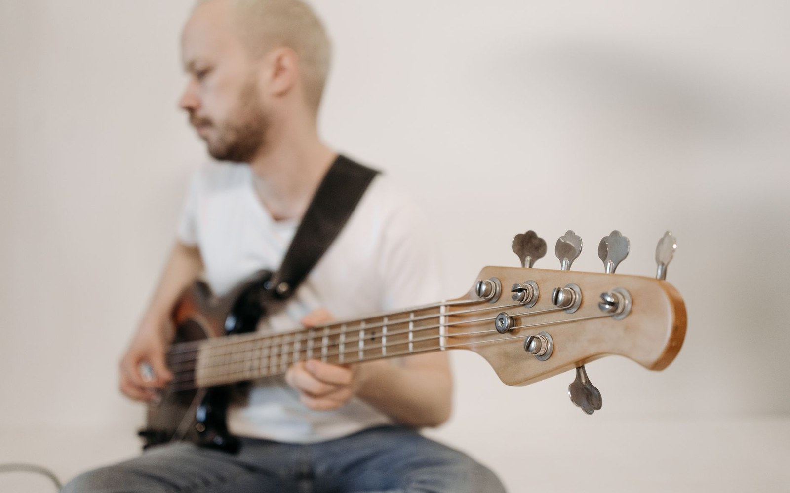 A bass guitar laid in an open flight case with plush-lined interior, the headstock and tuners in focus, the body receding into the case shadow