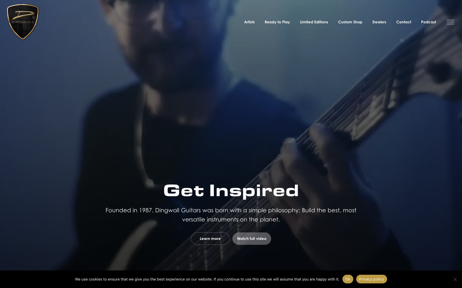 Musician playing a fanned-fret bass guitar in dim, blue-toned lighting