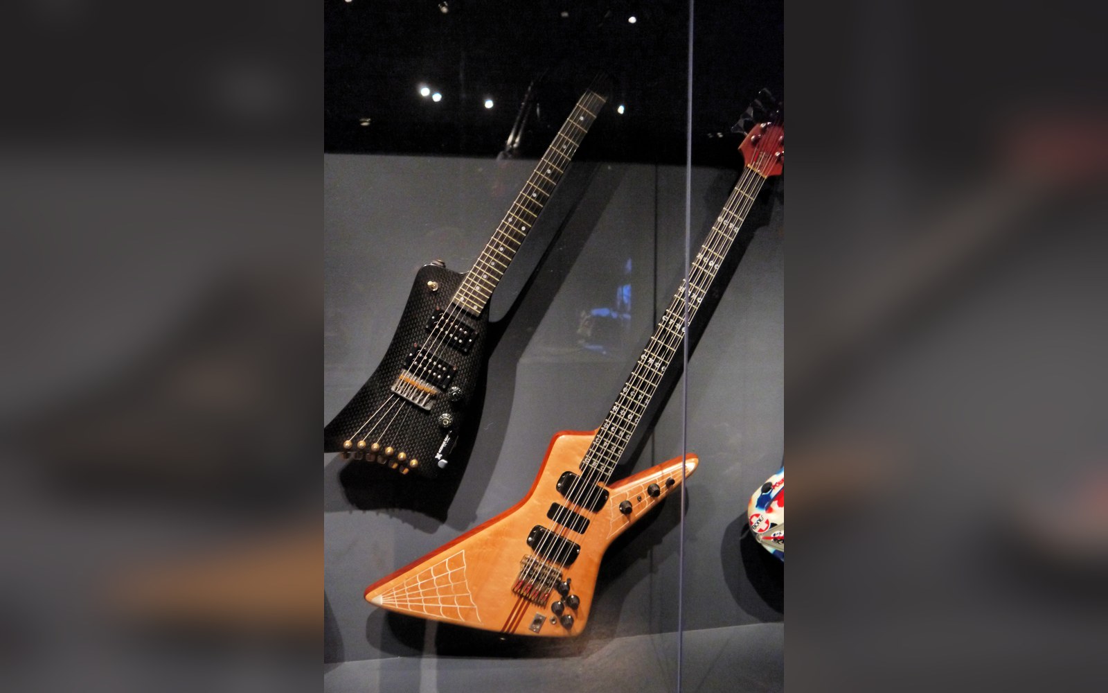 Angular Explorer-style electric guitars displayed in a glass museum case