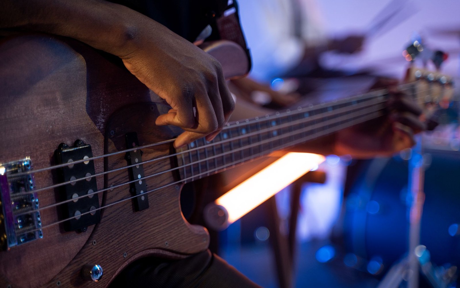 A close-up of a hand plucking the strings of a bass guitar on stage