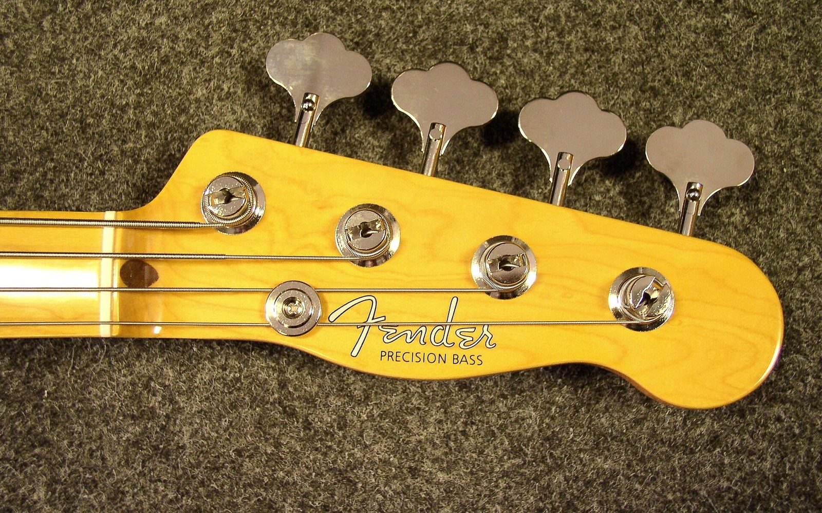 Fender Precision Bass headstock with tuning pegs on a fabric case background